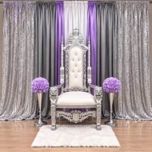 white and silver royal throne chair with colorful fabric draping, gold sequin backdrop and red floral arrangements by The Brat Shack Party Store.