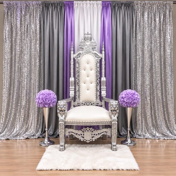 white and silver royal throne chair with colorful fabric draping, gold sequin backdrop and red floral arrangements by The Brat Shack Party Store.