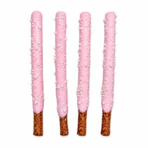 Four pink chocolate covered pretzel rods decorated with assorted white pearl sprinkles on a white background