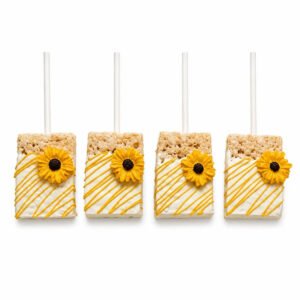 Four sunflower chocolate covered Rice Krispie treats on sticks with white coating, yellow drizzle and yellow sunflower decorations